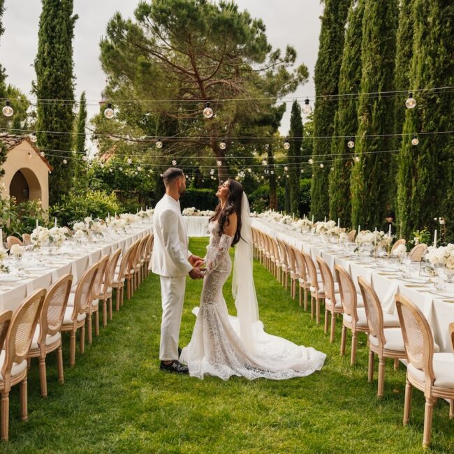 Brautpaar bei Hochzeit am Comer See, umgeben von einer festlich gedeckten Tafel im Garten.
